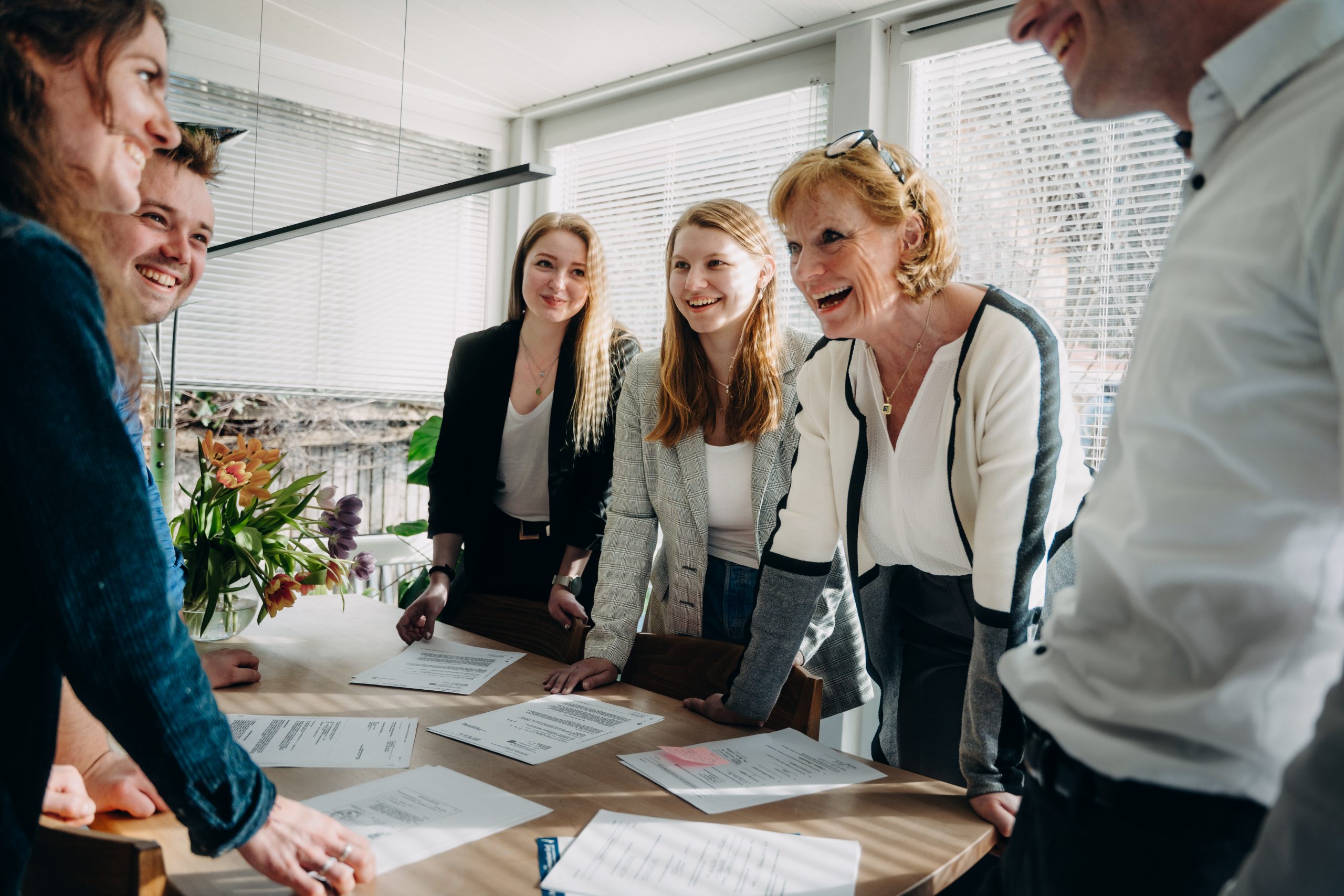 Gruppenaufnahme der Mitarbeitenden von Paul & Fischer bei einer Besprechung in einem hellen Raum 